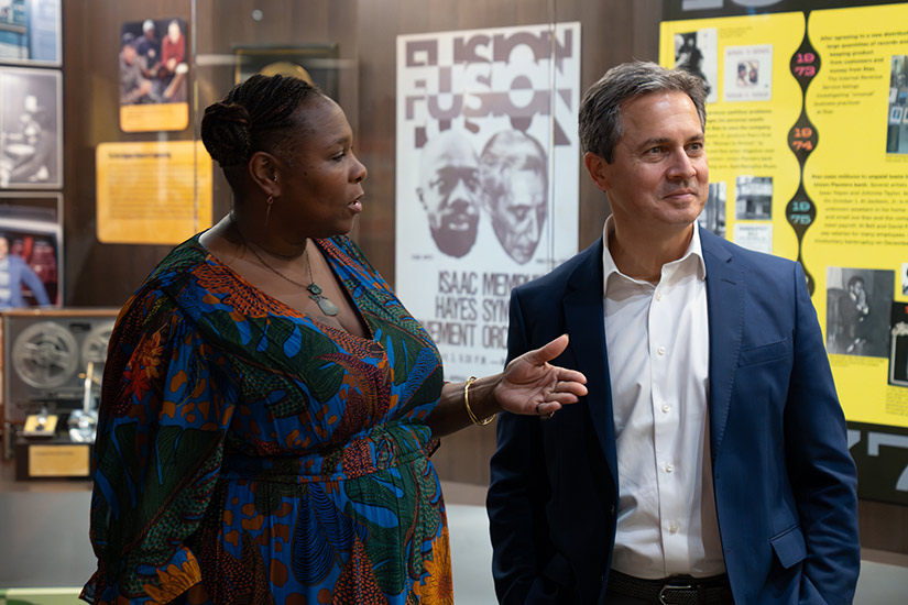 A woman speaks to Musalem in front of displays about music.