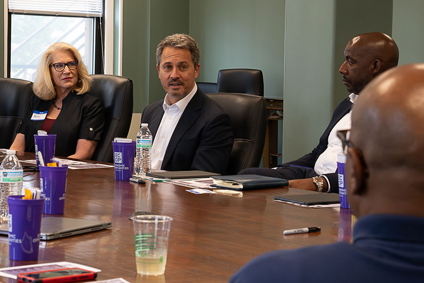 Musalem talks to a group of people seated at a conference table.