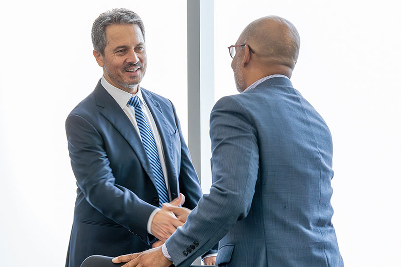 Musalem shakes hands with a man in business attire.