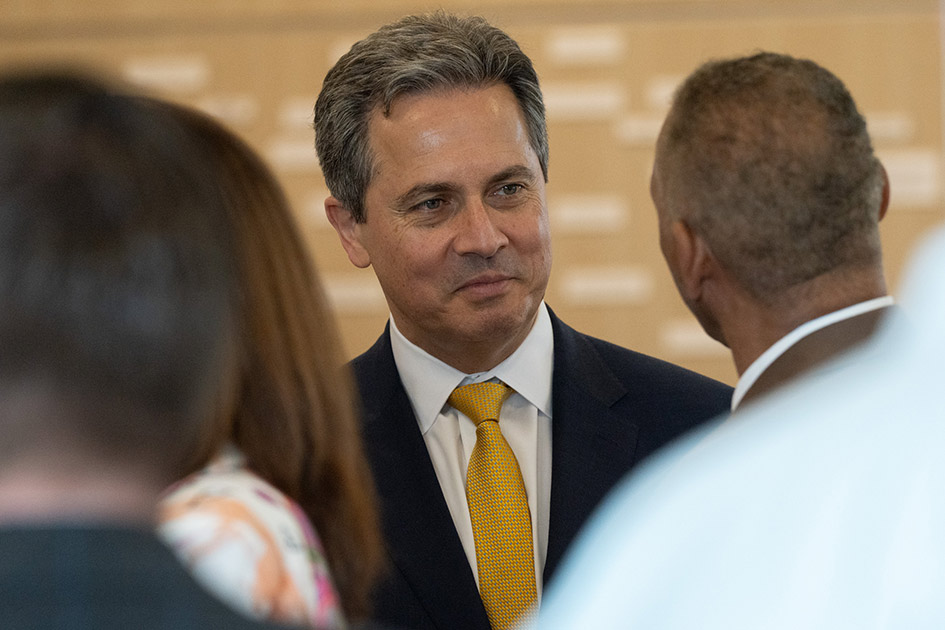 St. Louis Fed President Alberto Musalem talks with a man. Other people are in the foreground.