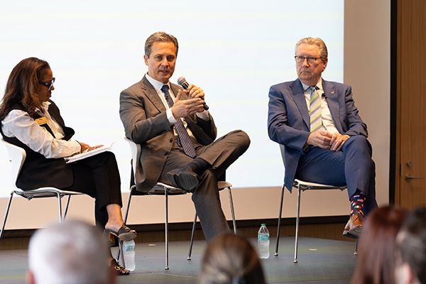 St. Louis Fed President Alberto Musalem and two others sit on a stage, with Musalem speaking to the audience.