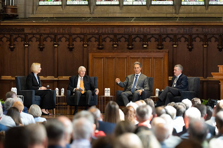 St. Louis Fed President Alberto Musalem speaks to an audience while seated with a woman and two other men on a stage.