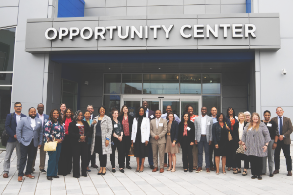A large group stands outside an Opportunity Center building.