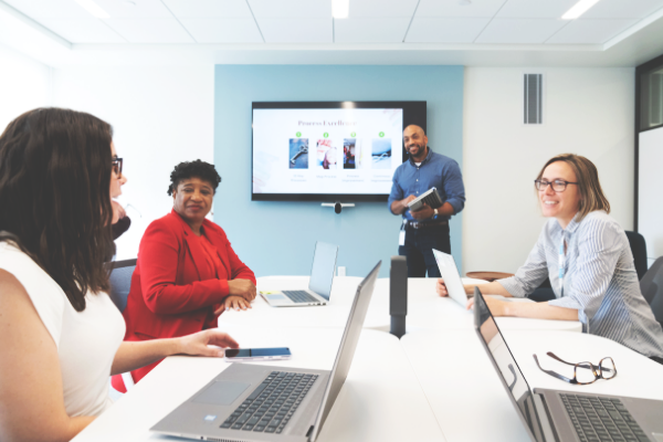 One person presenting to three other people in a conference room.