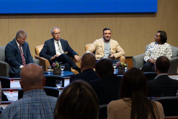 panel of 4 people speaking to a crowd in an auditorium