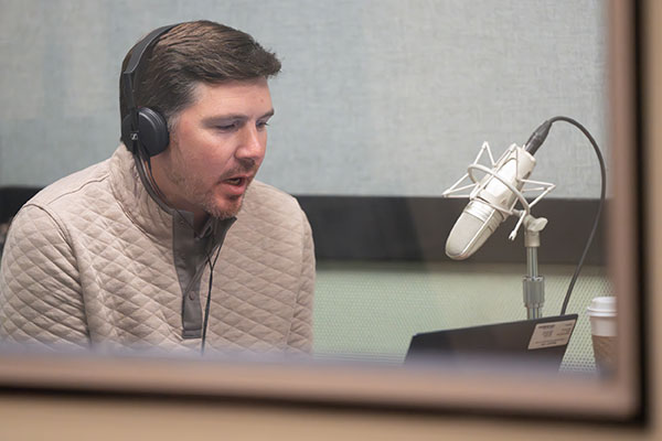 A man in casual attire speaking into a microphone.