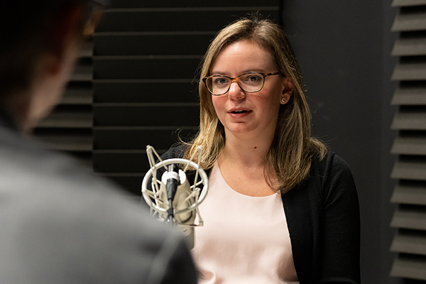 A woman, seated, speaking into a microphone.
