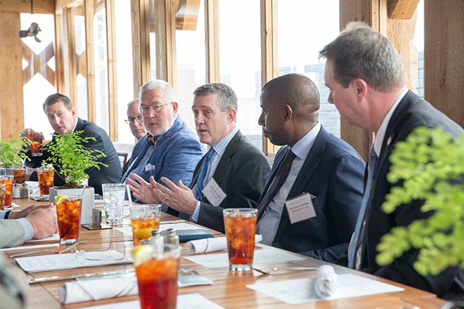 Jim Bullard and five executives talk while seated at a restaurant table.