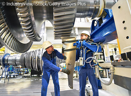 Two men wearing hard hats working in a factory.