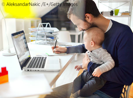 Man working on computer at home with child on his lap