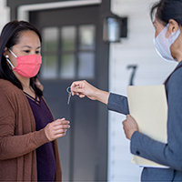 Lady with COVID mask on getting new home keys from her realtor