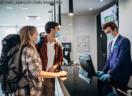 couple with masks checking into hotel room