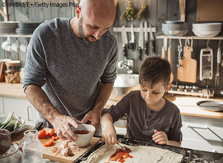 father and son making a pizza in their kitchen