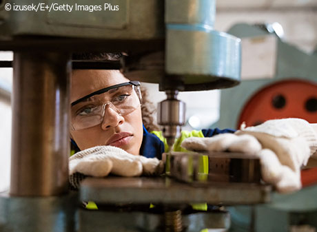 Female apprentice using yoke machine in factory.