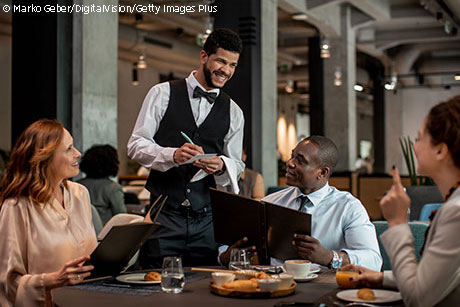 Waiter taking orders from guests in nice restaurant.