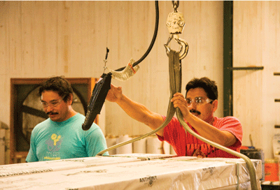 At Anthony Forest Products, Jeazon Fuentes uses a hoist to move laminated beams that have been wrapped for shipping.