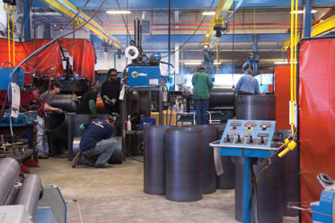 Employees of Grenada Stamping and Assembly make housings for air compressor tanks.