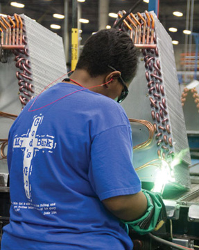 Tameka Black brazes distributor tubes onto a coil at Advanced Distributor Products.