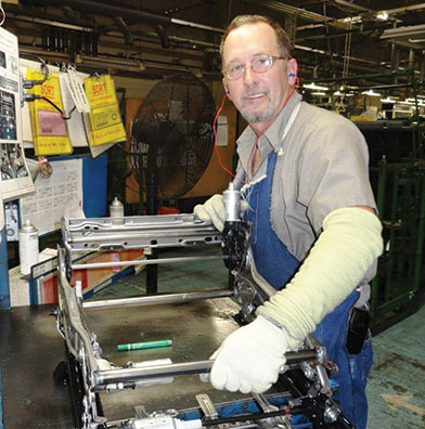 At auto parts maker Aisin U.S.A. Manufacturing, employee Gordon Bell works on a seat adjuster.