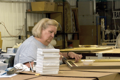 Liz Lester, one of John-Richard’s 250 employees in Greenwood, applies gold leaf to a picture frame. | St. Louis Fed