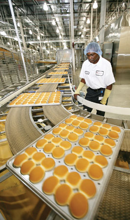 Terry Young, production technician at Flowers Baking Co., checks the quality of hamburger buns as they come out of the oven.