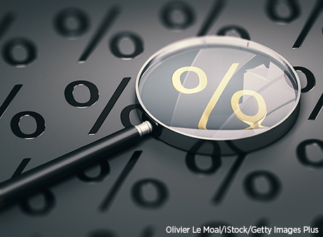 A magnifying glass over a black background covered with percentage symbols.