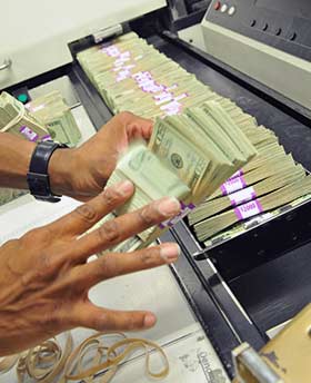 Currency employee sorting bills to detect counterfeit money