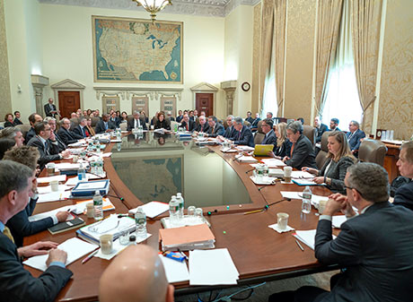 People seated around large wood table in a conference room