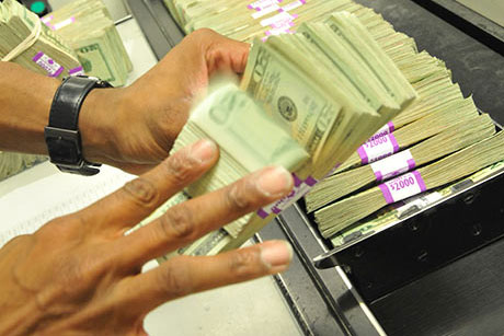 Man flips through stack of 20 dollar bills.