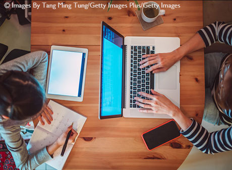 Direct above view of mom & daughter using laptop computer & tablet in workspace at home