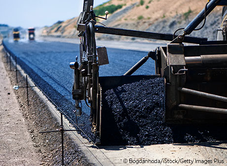 Blacktop pavement being laid on road.